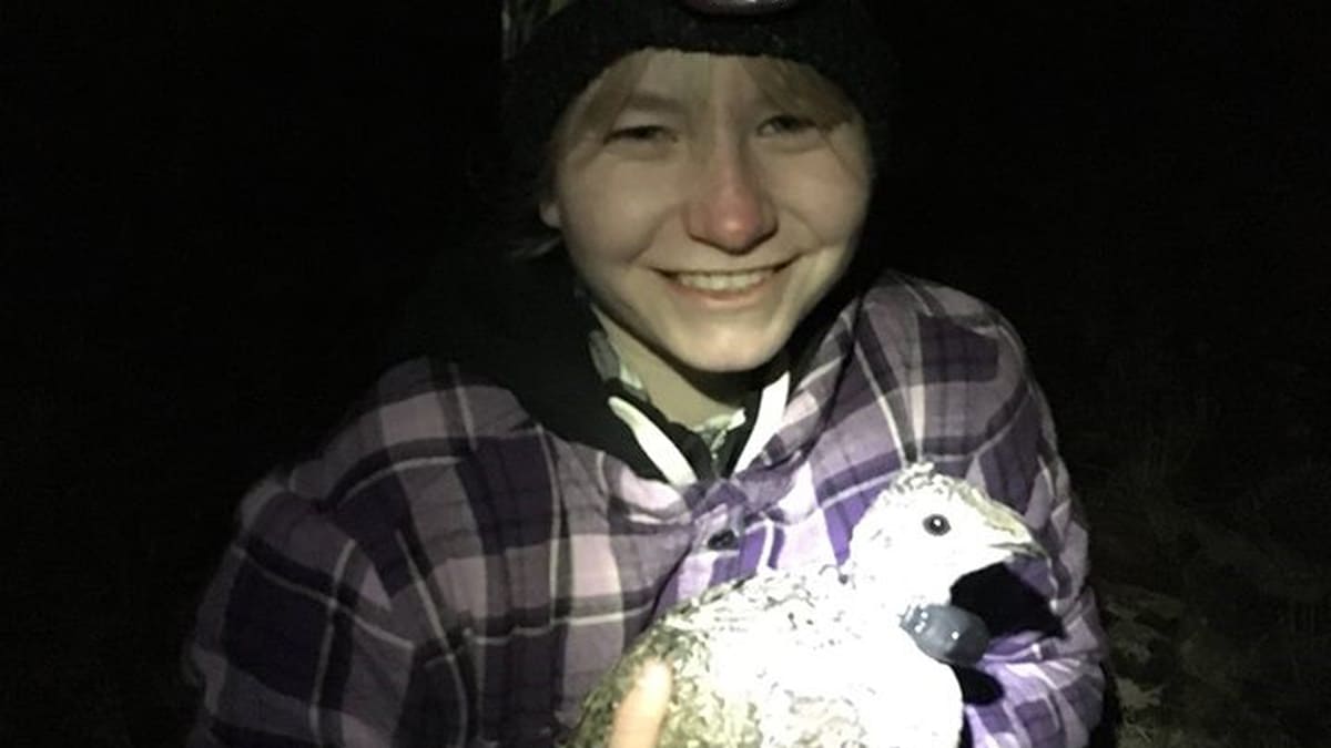 Lohman in the dark on a range wearing a headlamp holding a sage grouse