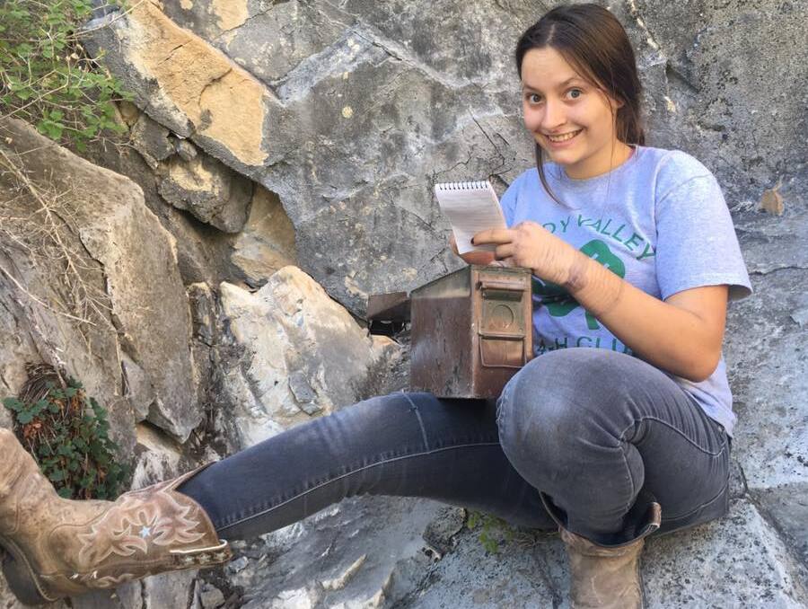 4-H'er who hiked to and located a geocache now updates its contents.