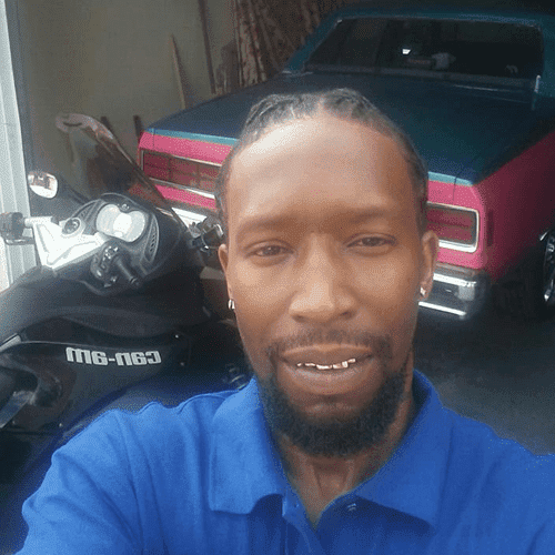 Cedric Bell near a motorcycle and sports car