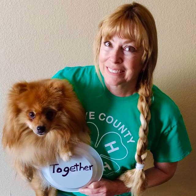 Lisa Remington in a Nye County 4-H shirt, holding a dog and a sign that says 'Together'