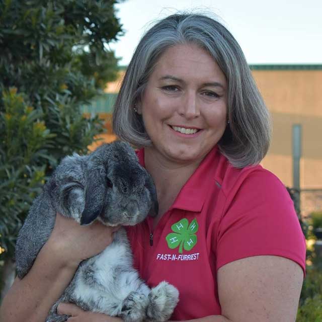 Susan Dreyfus, wearing a brightly colored Fast N Furriest 4-H shirt and holding a rabbit