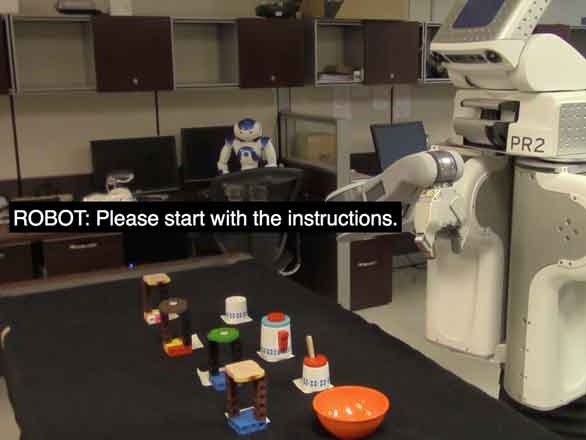 A PR2 robot in front of a table with a tea pot and cups. Caption text on the screen reads: ROBOT: Please start with the instructions.