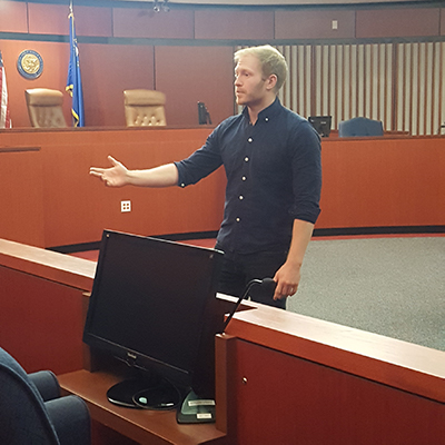 Student giving a speech to a mock jury in a courtroom.