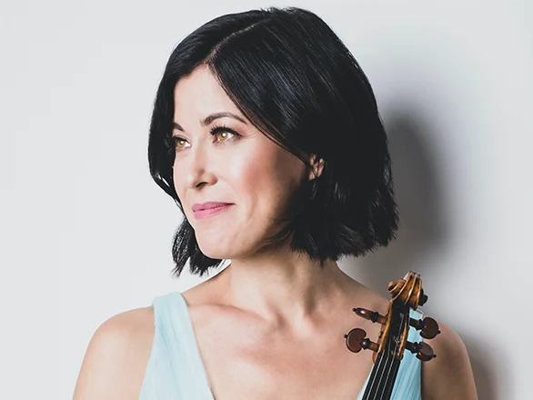 Jennifer Frautschi wears a blue dress and holds a violin and poses for a photo.