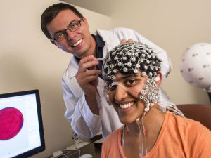 A researcher attaching headgear with electrodes to a research subject for a neuroscience experiment 