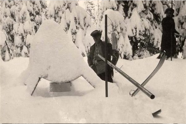 Researcher standing in deep snow next to a equipment