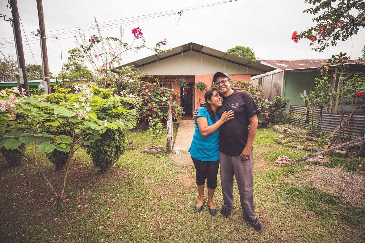 Humberto and Daysie Garcia in front of their home, which is surrounded by lush vegetation