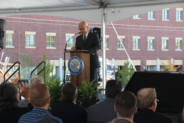 Dean Manos Maragakis addresses a crowd of dignitaries 