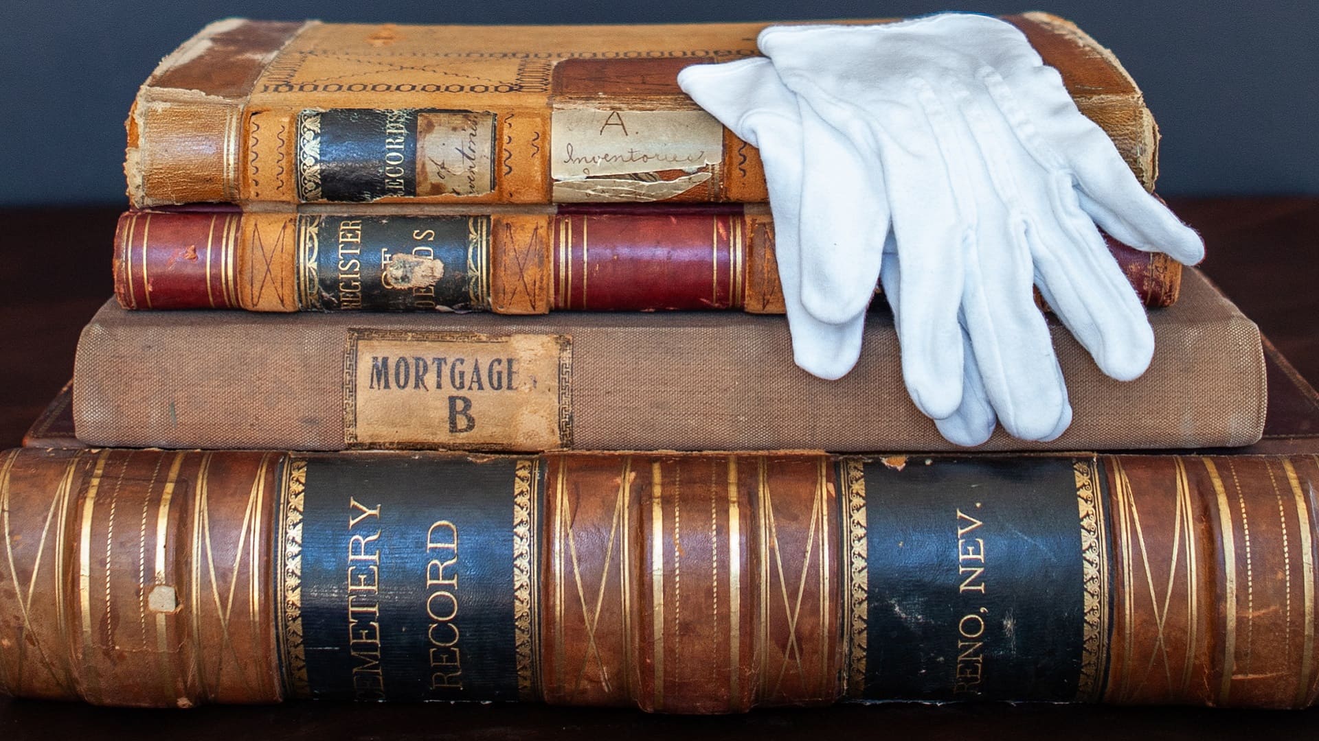 White gloves sit atop a stack of old books and ledgers from Reno's history