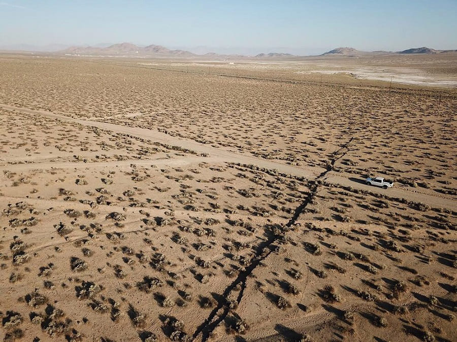 An aerial view of the Ridgecrest quake fault stretching across the desert with a truck parked next to it