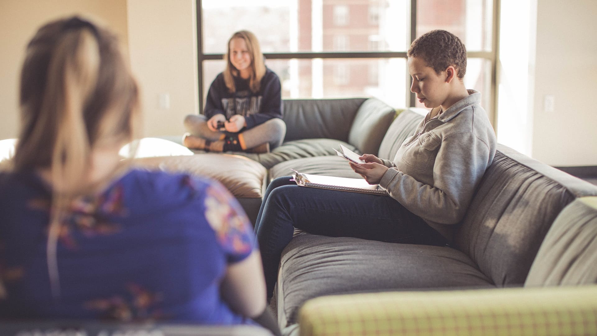 Three students in the WiSE program sitting on couches in the dorm studying