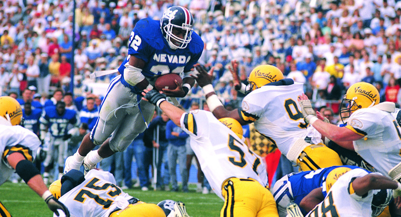 Charvez Foger gripping a football while he battles through tough defense on the field