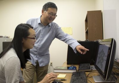 Faculty members Qi An and Xiaokun Yang shown working on a computer-based project.
