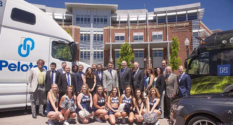 Governor Sandoval and a crowd outside Joe Crowley Student Union in between three autonomous vehicles 