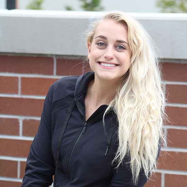 Jilliann Paraguirre poses in front of a brick wall