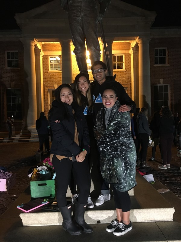 Duenas and Phi Delta Epsilon members smiling in front of the Mackay statue