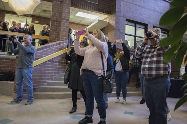 Parents take photos on their phones in the atrium.