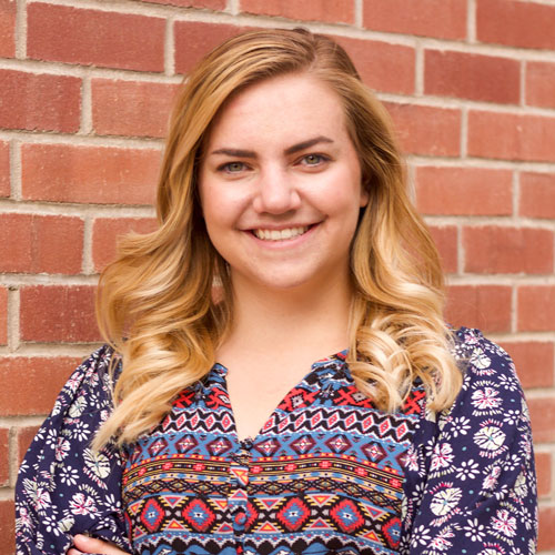 Woman poses in front of brick wall