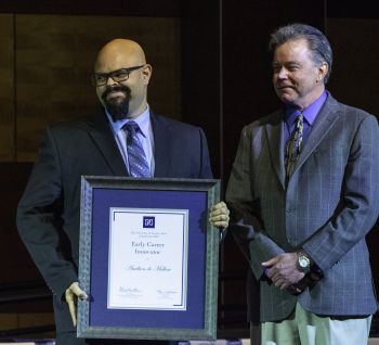 University faculty member is presented a plaque from the Provost