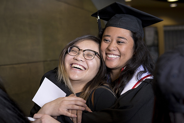 Graduates laughing and hugging at the Asian American & Pacific Islander Graduate Celebration
