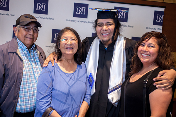 A smiling graduate with family members at the American Indian & Alaskan Native Graduate Celebration