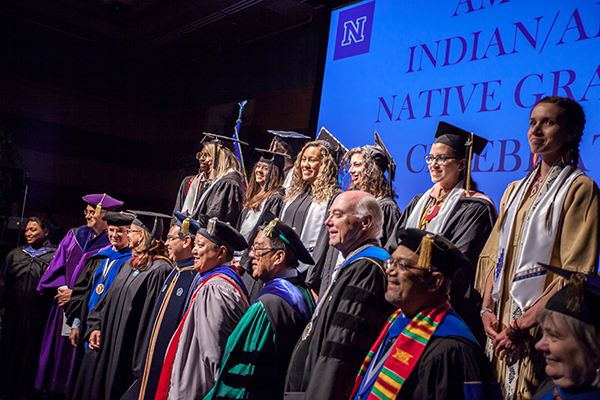 Graduates and faculty on stage at the American Indian & Alaskan Native Graduate Celebration