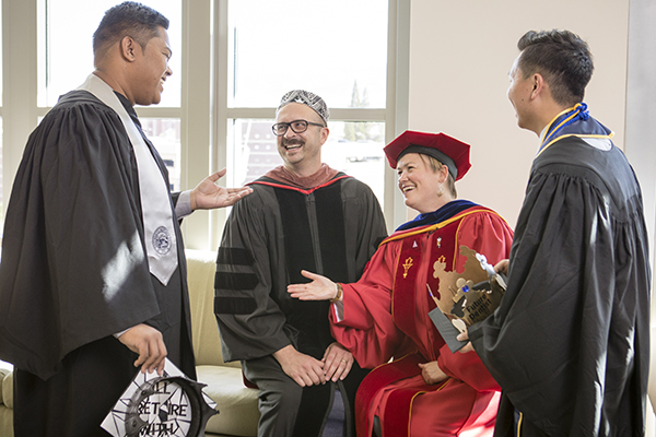 Graduates and faculty members laugh together at the Lavender Graduate Celebration