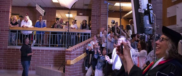 People take photos of the graduates in the Reynolds School atrium.