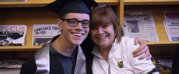 A student and family member pose indoors.