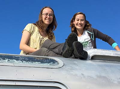 Allison Blair and friend sitting on top of airstream trailer