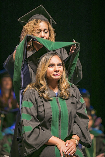 Graduating medical student Emmanuelle Garcia-Rider is hooded by her mother, Diane Garcia
