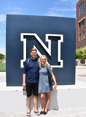 Gelard and Holzer stand together in front of the university logo