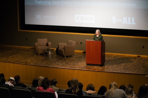 Woman stands at podium speaking to audience.