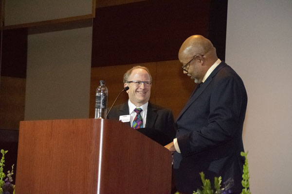 Leonard Pitts Jr. stands on stage next to dean Stavitsky.