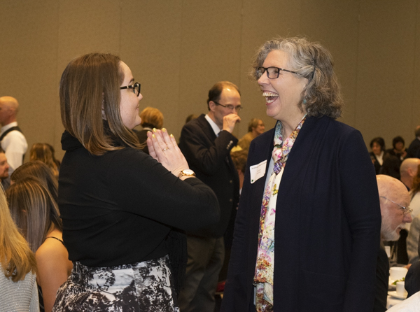 University faculty and guests chat indoors.