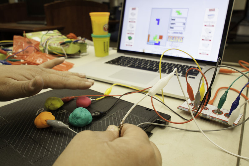 A student uses a makey-makey kit to control a game.