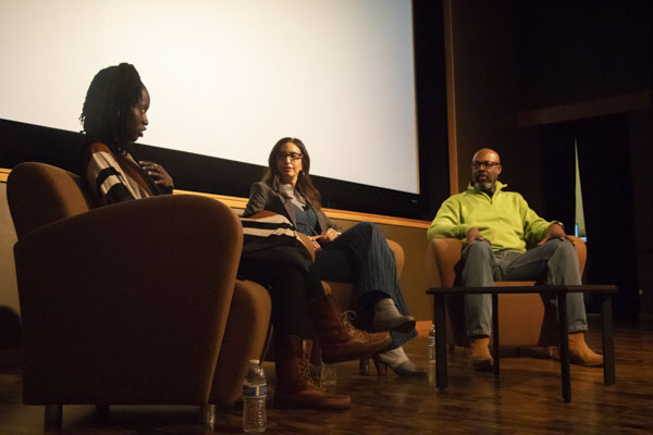 Faculty member and two women sit on stage.