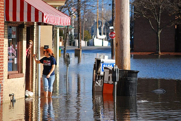 Woman walks through water on a flooded street.