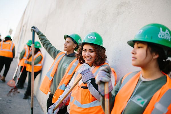 Students working with the LA Corps smile against a wall..