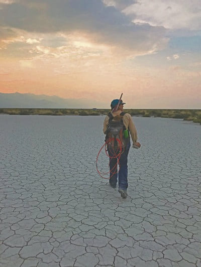 Field worker walking across a dry lake bed