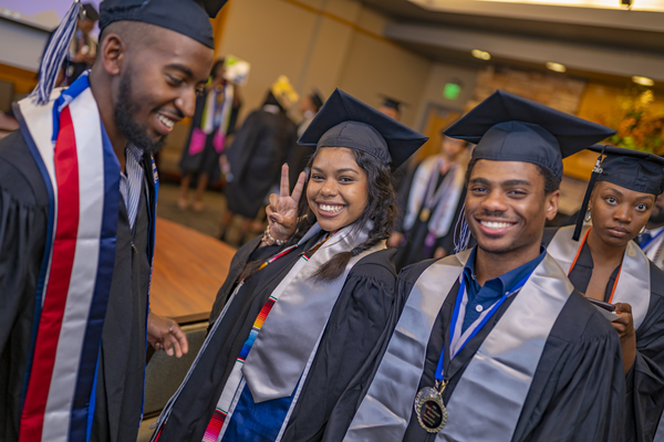 Smiling graduates at the African Diaspora Graduate Celebration, one making a peace sign