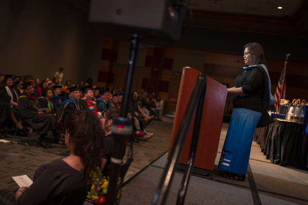 A student speaker addressing the audience at the American Indian & Alaskan Native Graduate Celebration