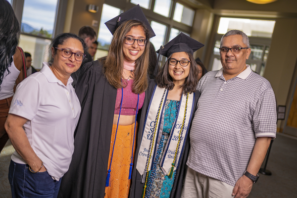 Two graduates with parents at the Asian American & Pacific Islander Graduate Celebration