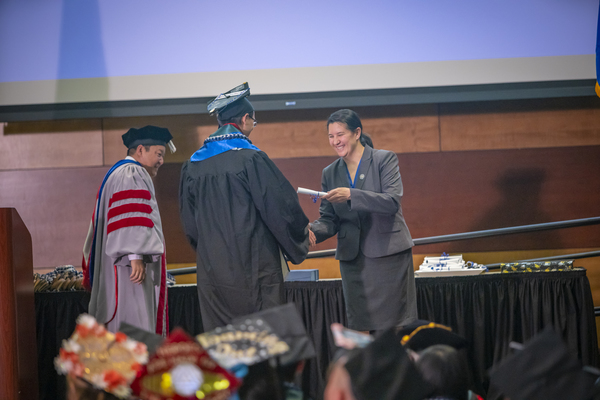 A graduate recieving honors on stage at the Asian American & Pacific Islander Graduate Celebration