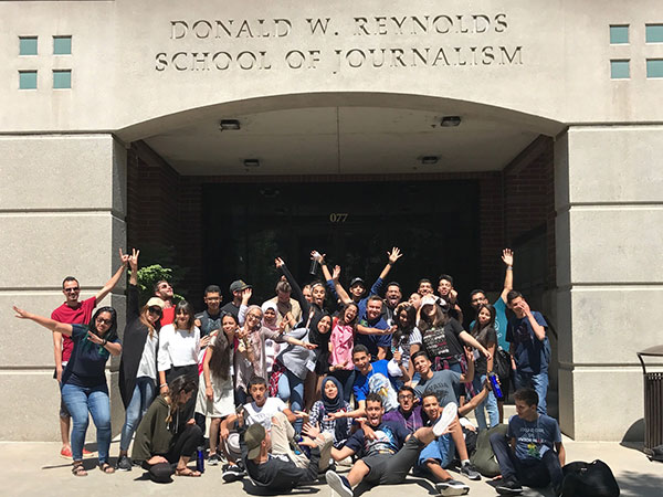 Students and a faculty member pose in front of the Reynolds School.