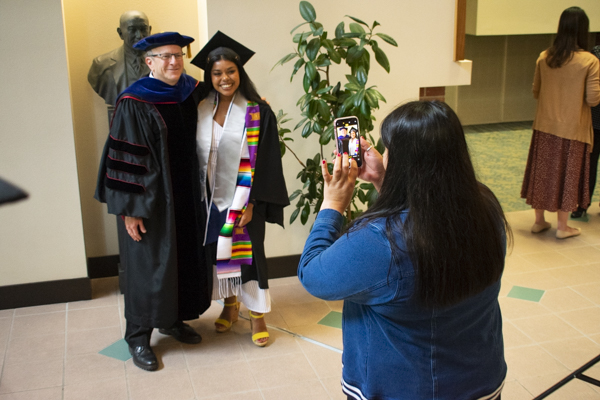 A parent takes a picture of her student and the dean with her phone.