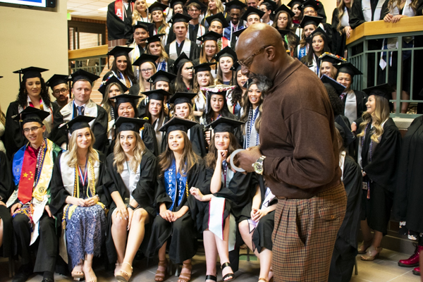 A faculty member speaks to the students in the atrium.