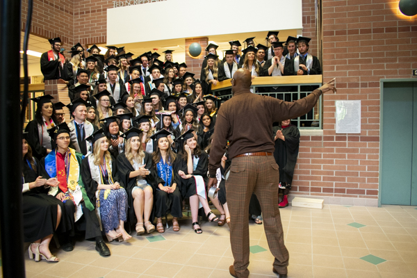 A faculty member speaks to the students in the atrium.