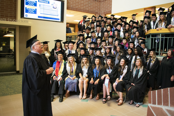 A faculty member speaks to the students in the atrium.