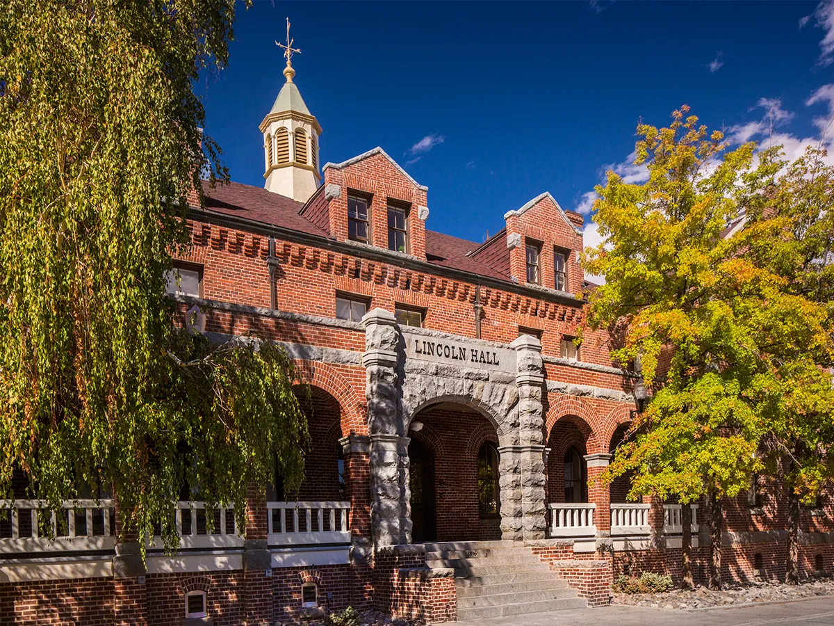 A view of Lincoln Hall, with large trees and the sign above the entrance that reads "Lincoln Hall."